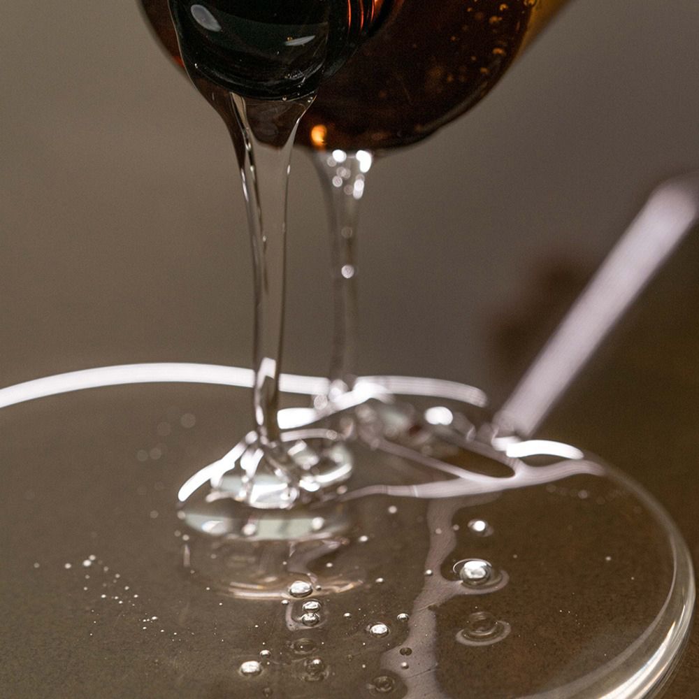 Shampoo trasparente versato da una bottiglia. Forma un cerchio liquido su una superficie.