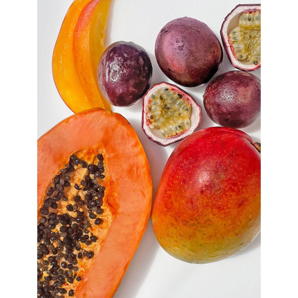 Papaya, mango e frutti della passione su sfondo bianco. Vista dall'alto. Alcuni frutti sono tagliati a metà.