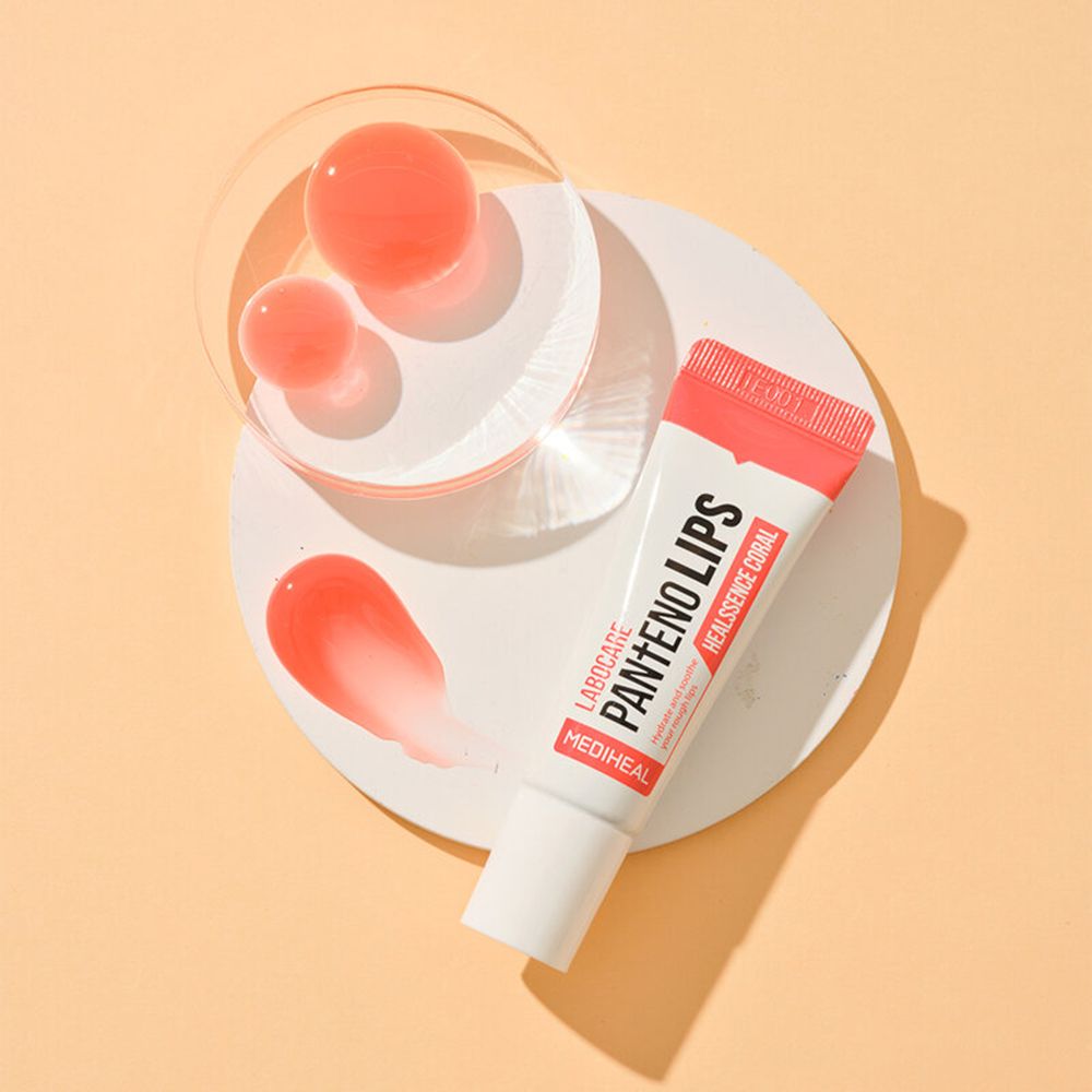 Balsamo labbra colorato in tubo. Su sfondo bianco, macchie e sfere rosa. MEDIHEAL Labocare Pantenolips Healssence Coral.