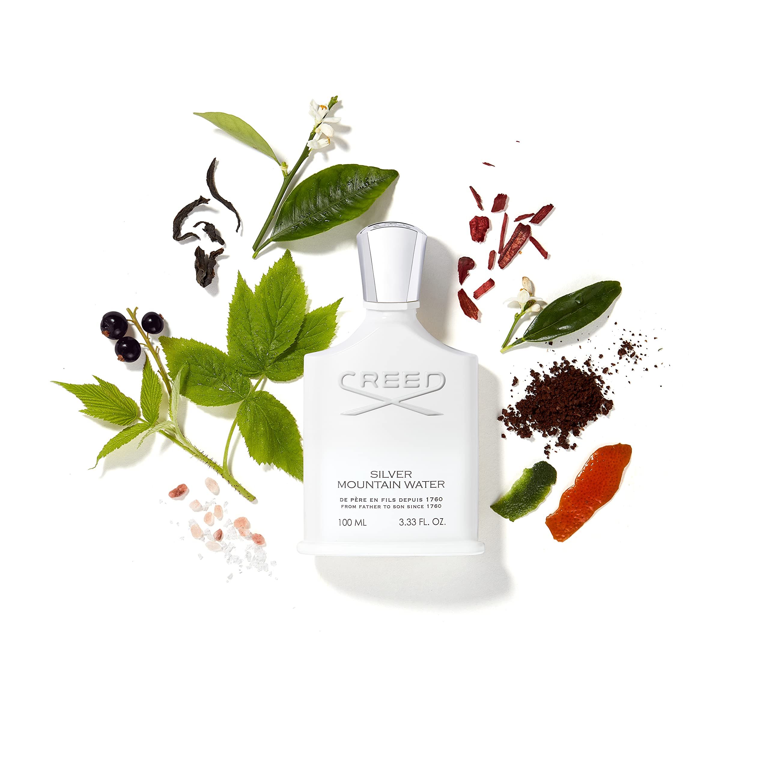 Flacone bianco circondato da piante e frutta. Scritta: Creed Silver Mountain Water.