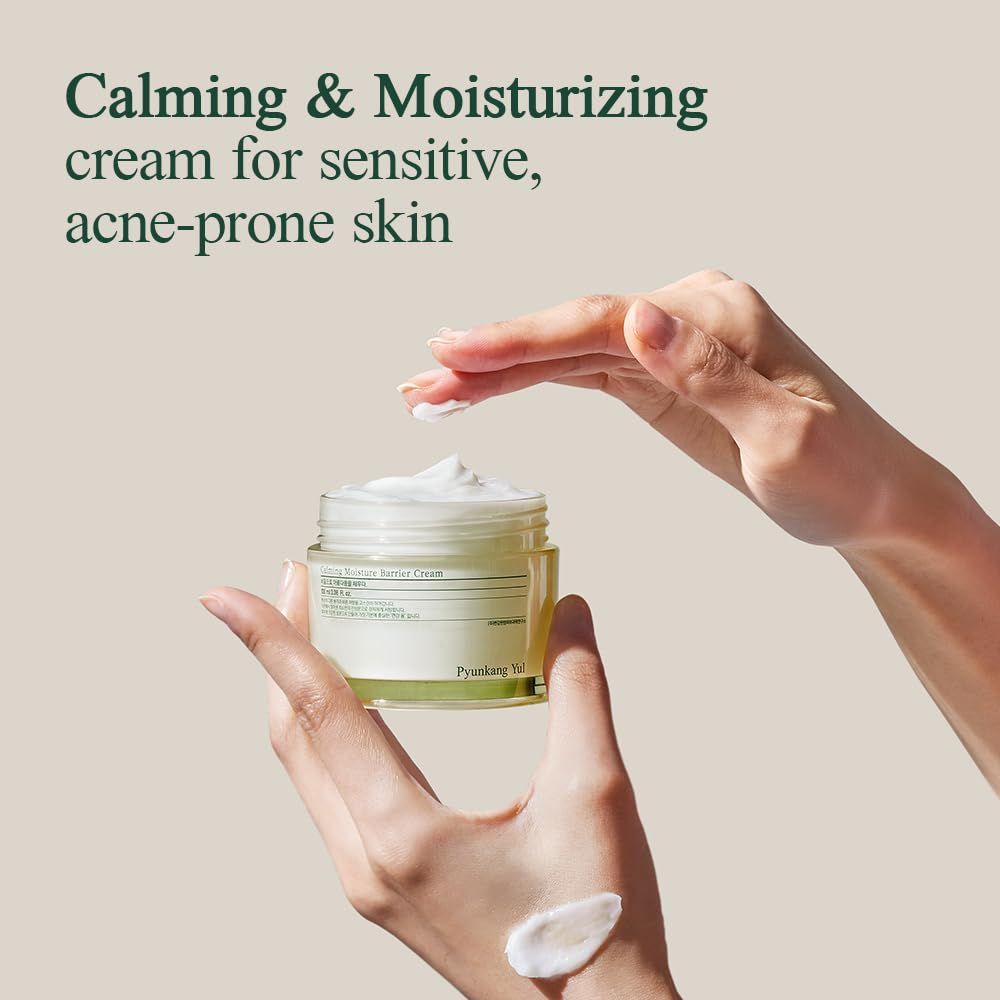 Mani che tengono un vasetto di crema. La crema viene applicata sulla mano. Testo: Calming & Moisturizing cream for sensitive, acne-prone skin.