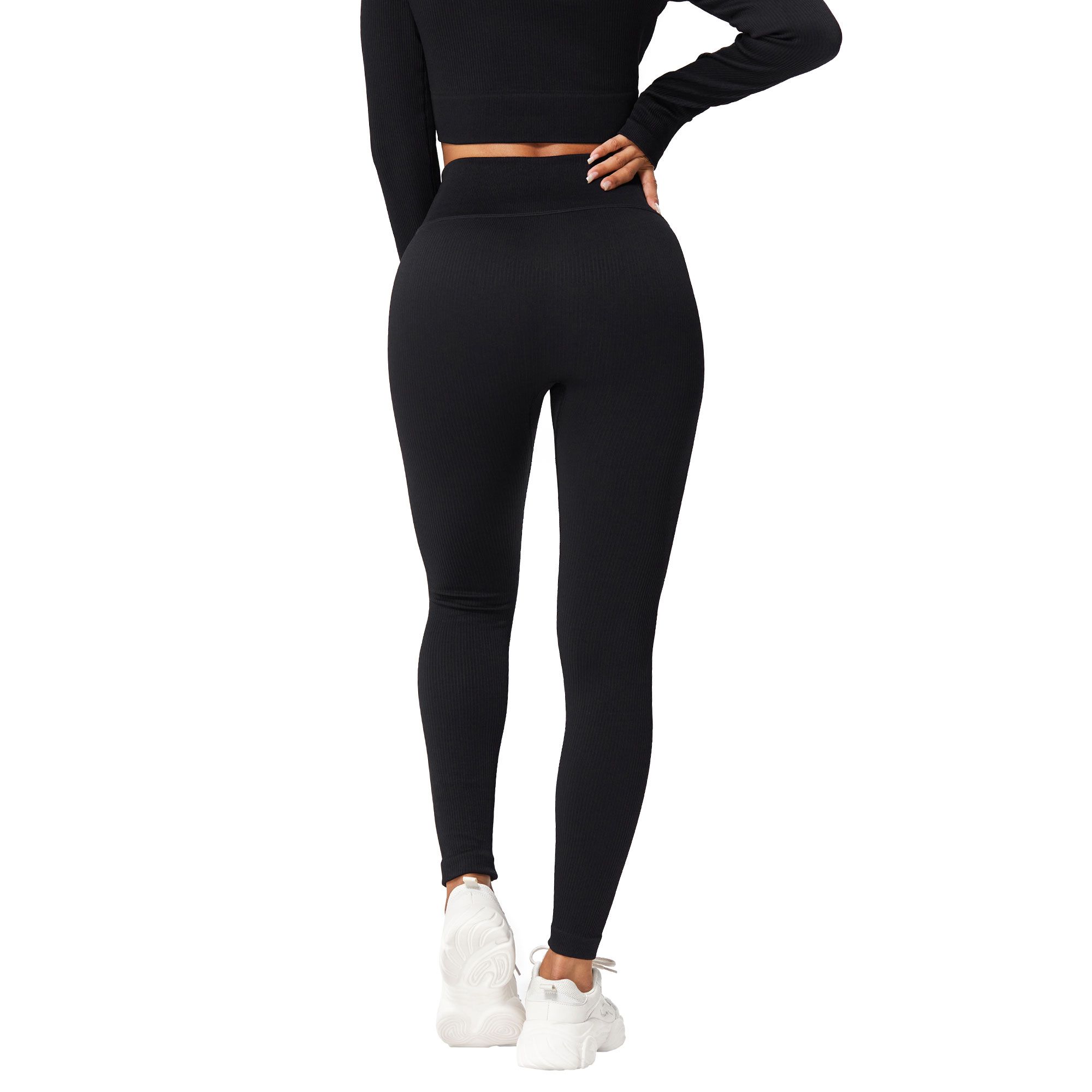 Leggings neri aderenti e top a maniche lunghe, indossati con scarpe da ginnastica bianche.