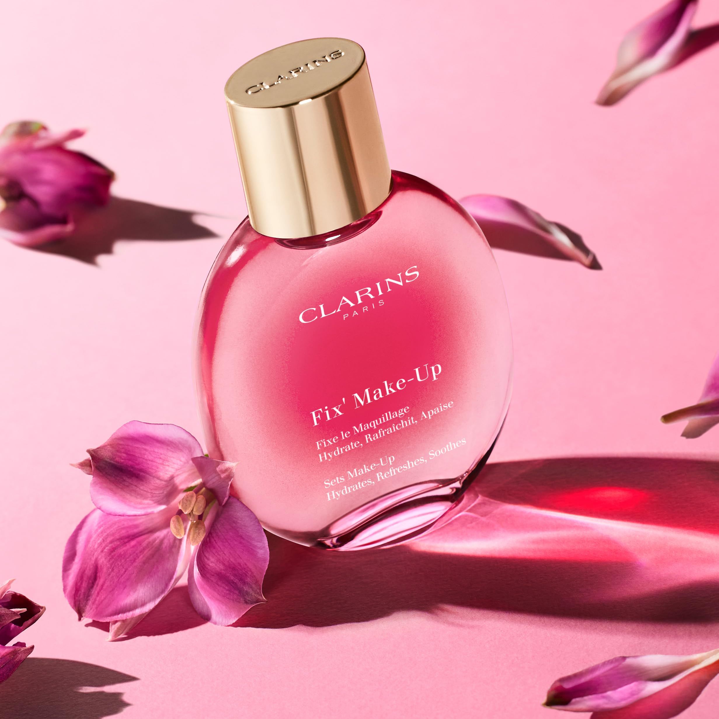 Flacone rosa con tappo dorato, circondato da petali rosa. Testo: Fix' Make-Up. Sfondo: rosa.