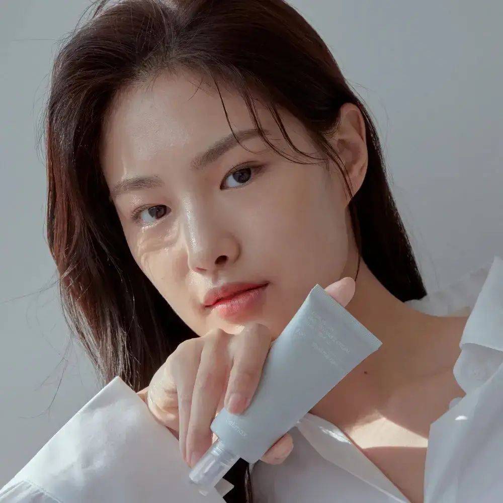 Donna con pelle. Indossa una camicia bianca. La pelle è liscia e sana.