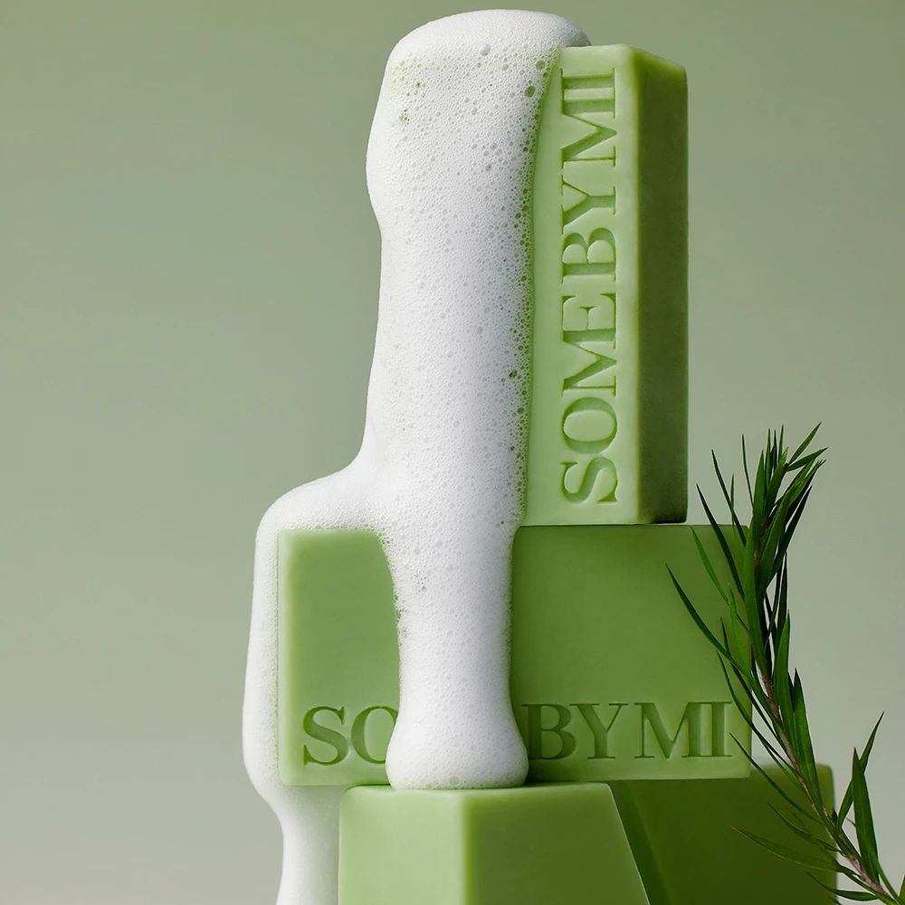 Panetti di sapone verdi impilati e coperti di schiuma, con un rametto.