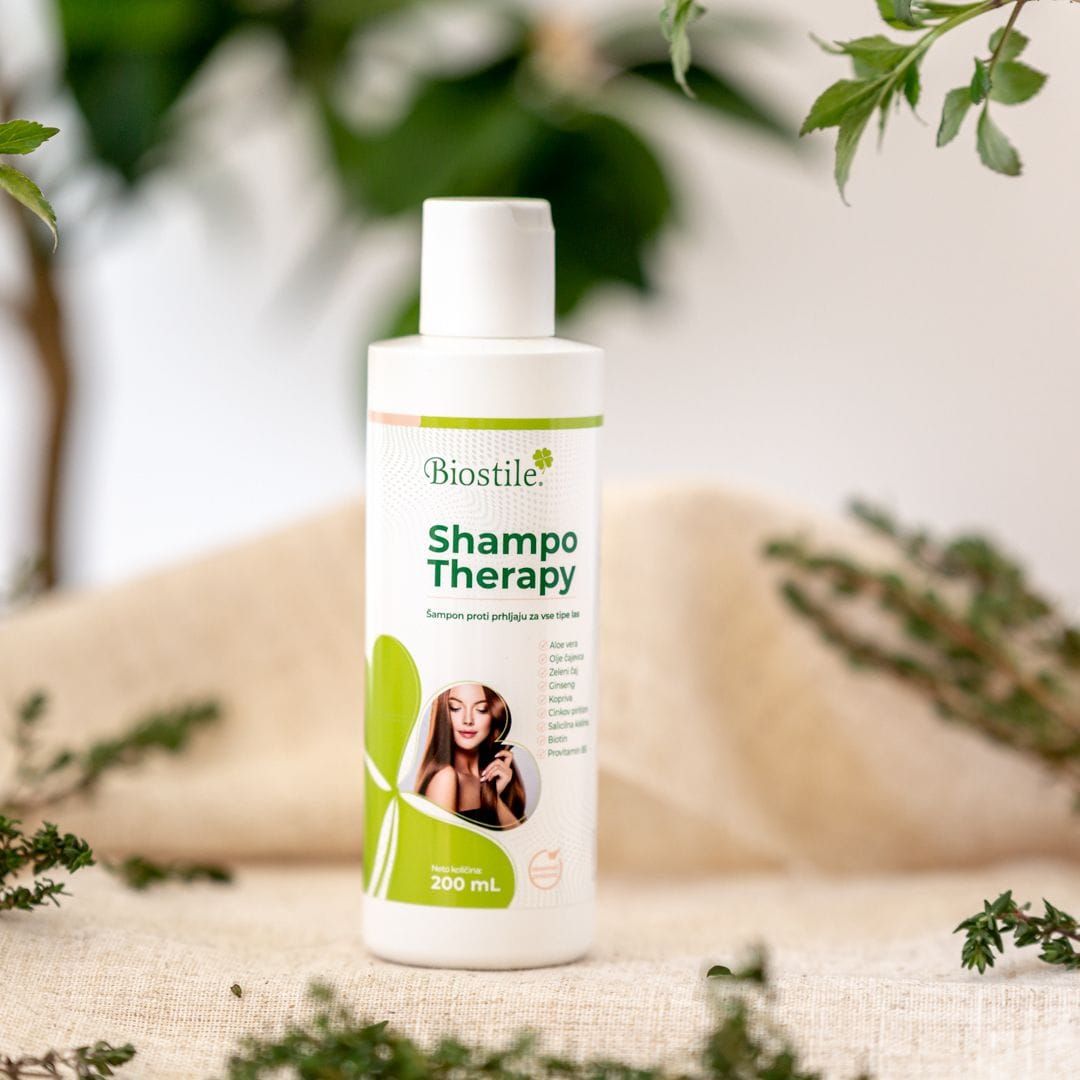 Flacone Biostile Shampoo Therapy su un tavolo. Sfondo con piante.