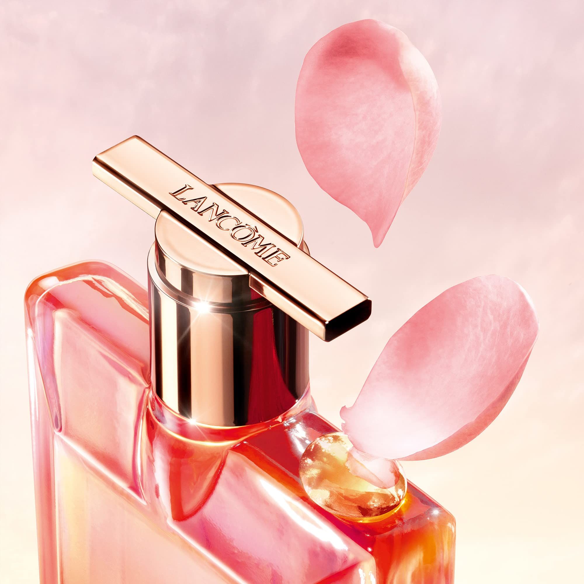 Primo piano di un flacone con tappo dorato. 'Lancôme' sul tappo. Due petali.