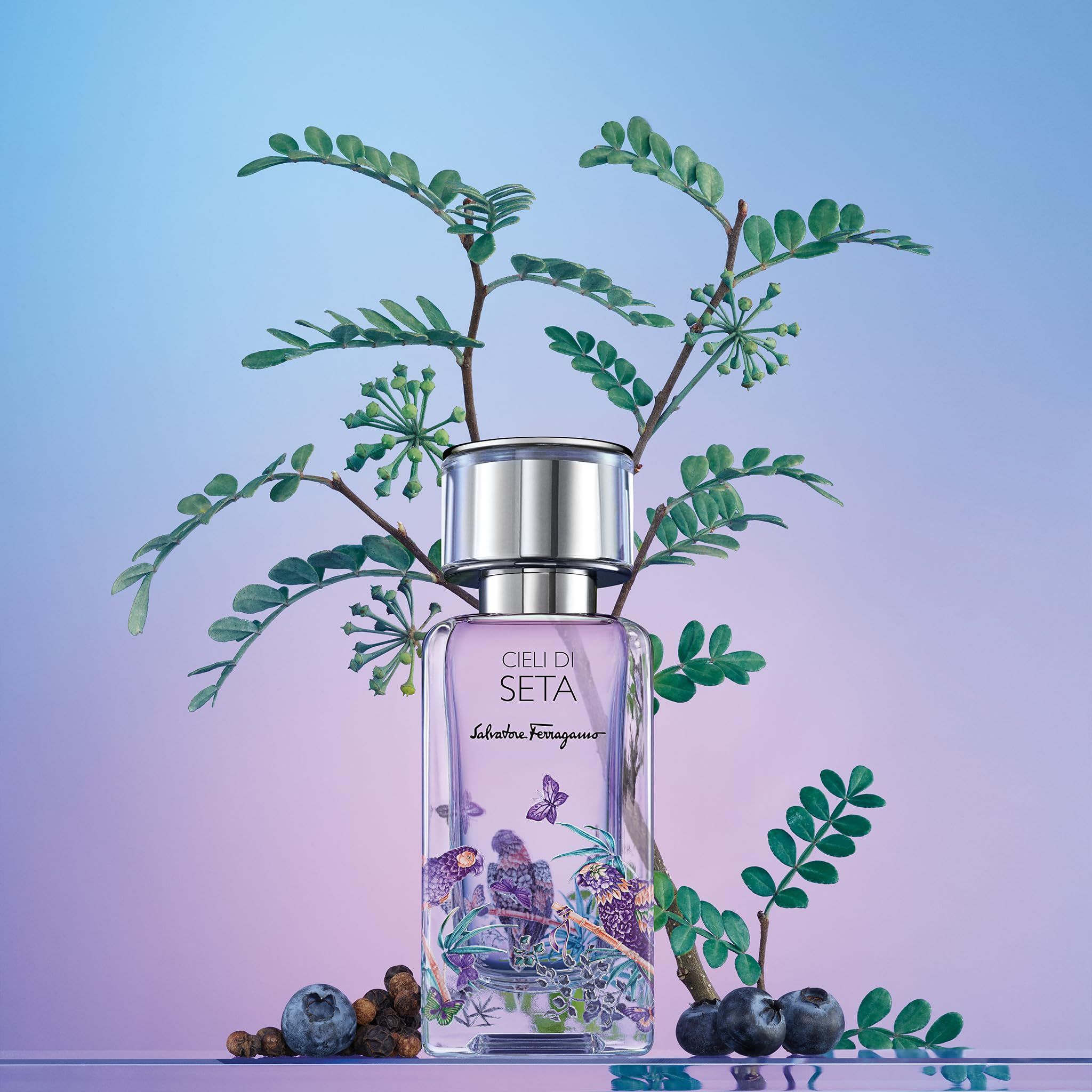 Salvatore Ferragamo Cieli di Seta EdP Nat. Spray. Flacone su sfondo floreale con foglie, bacche e farfalle.