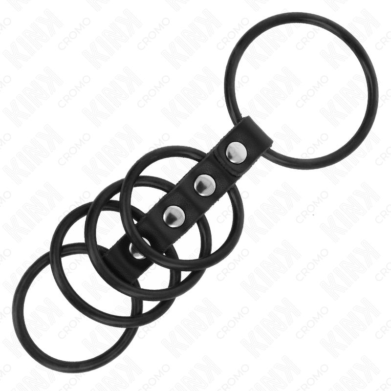Anelli per pene neri in silicone, collegati da una cinghia in pelle con tre rivetti. Su sfondo bianco.