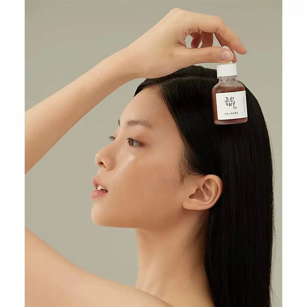 Donna tiene flacone Beauty of Joseon Revive Serum. Viso con siero.
