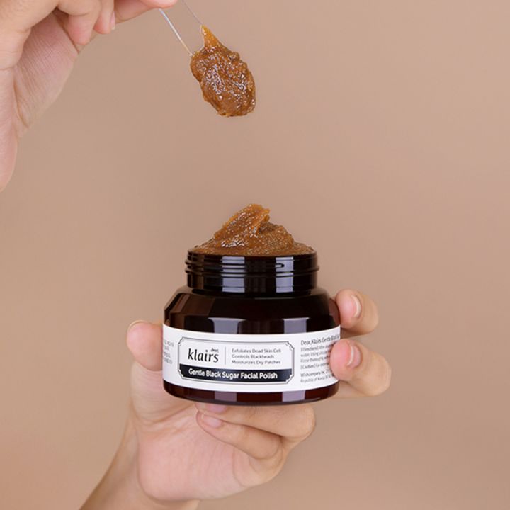 Pasta esfoliante allo zucchero marrone in un barattolo. Un cucchiaio ne contiene una porzione. Scritta: Dear Klairs Gentle Black Sugar Facial Polish.