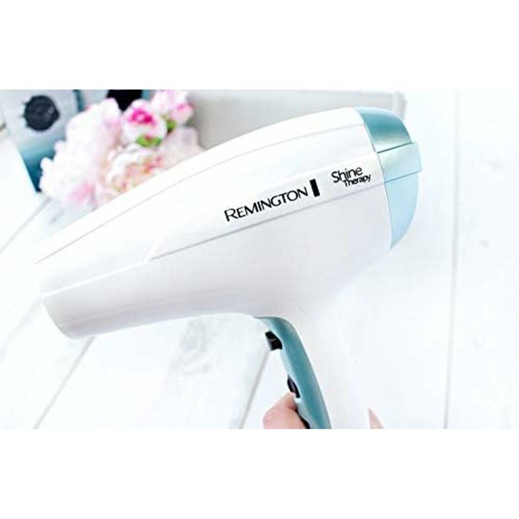 Asciugacapelli bianco. Marchio Remington Shine Therapy. Dettagli blu. Tenuto in mano.