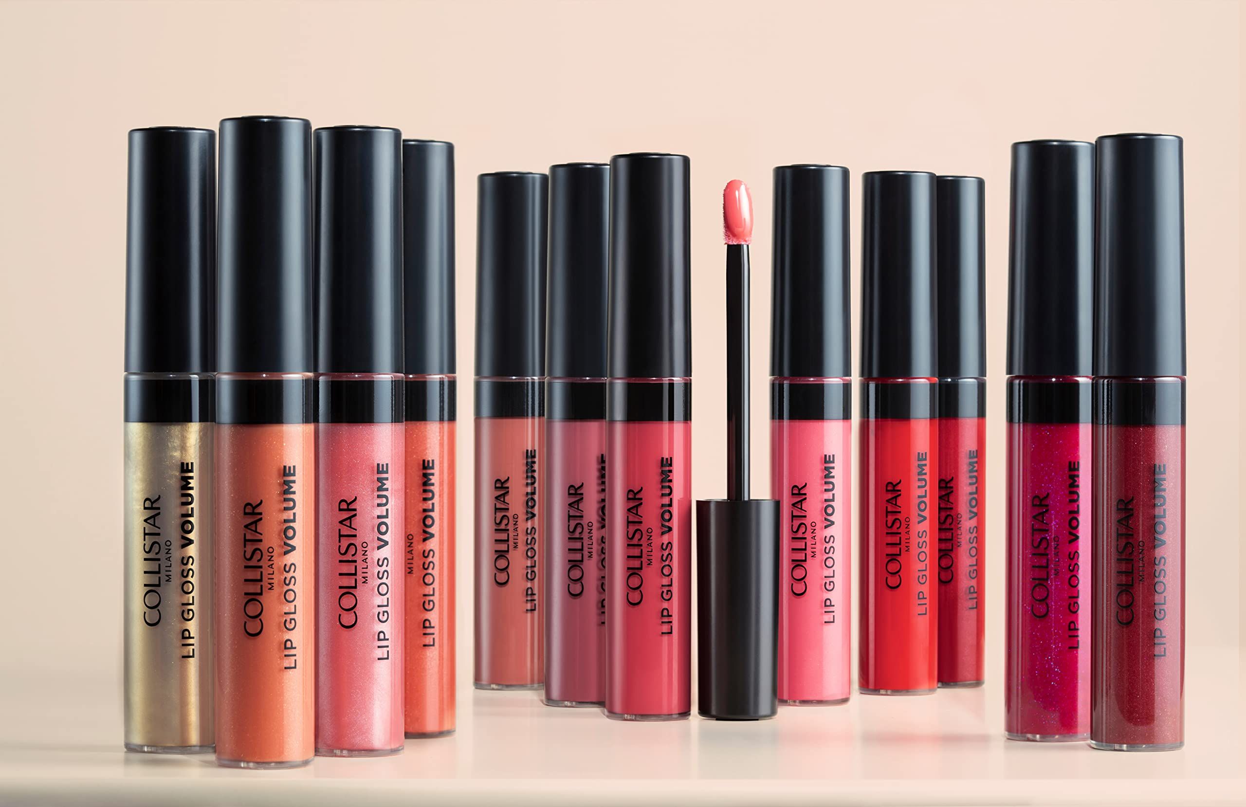 Una fila di tubi di lucidalabbra con tappi neri. Sui tubi è scritto "COLLISTAR LIP GLOSS VOLUME". Un applicatore è visibile.