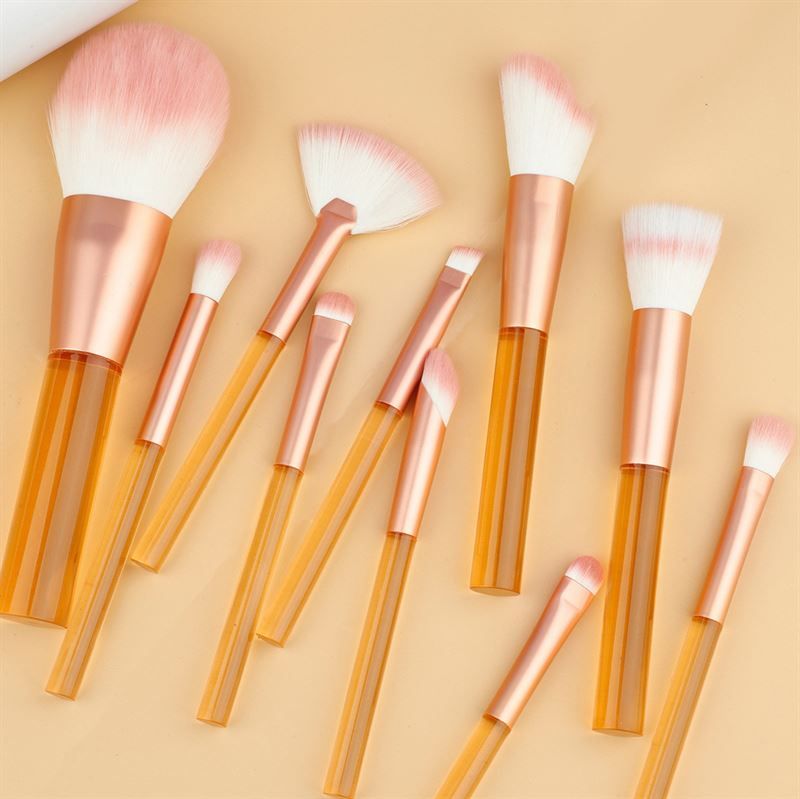 Set di pennelli per trucco con manici arancioni trasparenti e setole rosa. Varie forme e dimensioni.