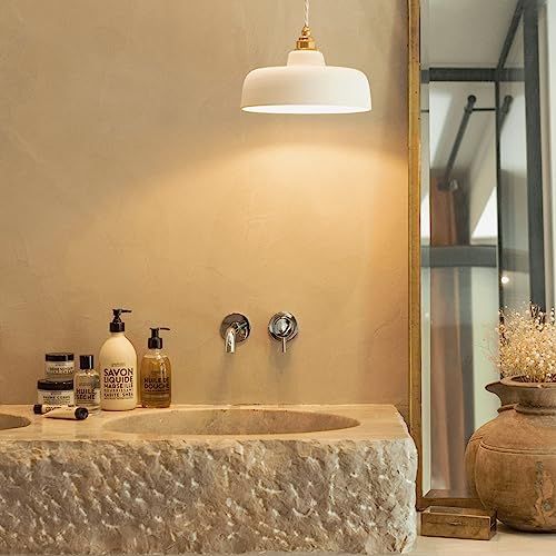 Bagno con lavabo, flaconi di sapone e specchio. Un flacone con la scritta SAVON LIQUIDE MARSEILLE.