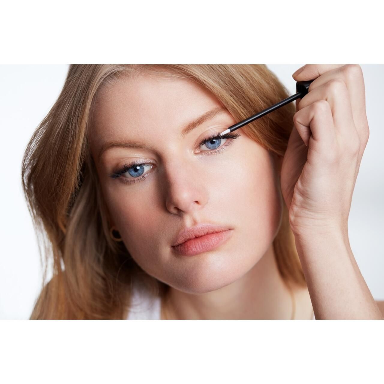 Donna applica siero. Donna bionda applica siero sull'occhio con applicatore.