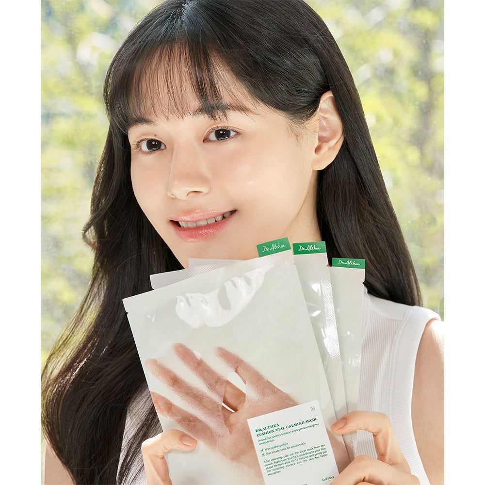 Una donna tiene diverse maschere lenitive Dr. Althea Cushion Veil davanti a sé.