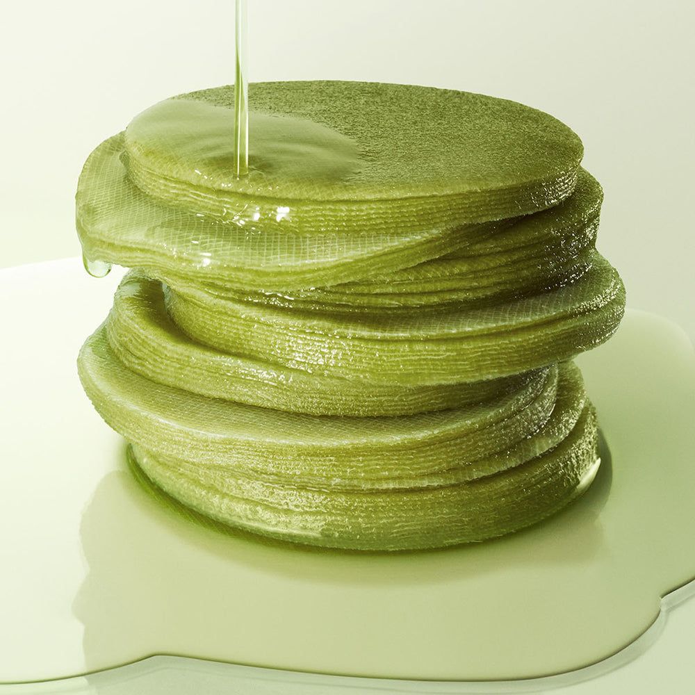 Salviette al tè matcha verdi impilate, irrorate di liquido.