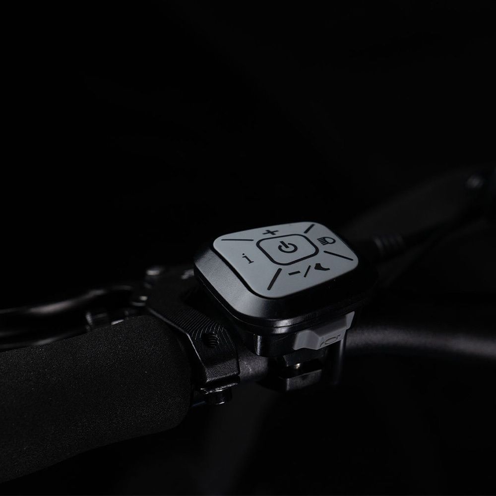 Comando manubrio con pulsanti. Sfondo nero. Simboli per luce, alimentazione e altro.