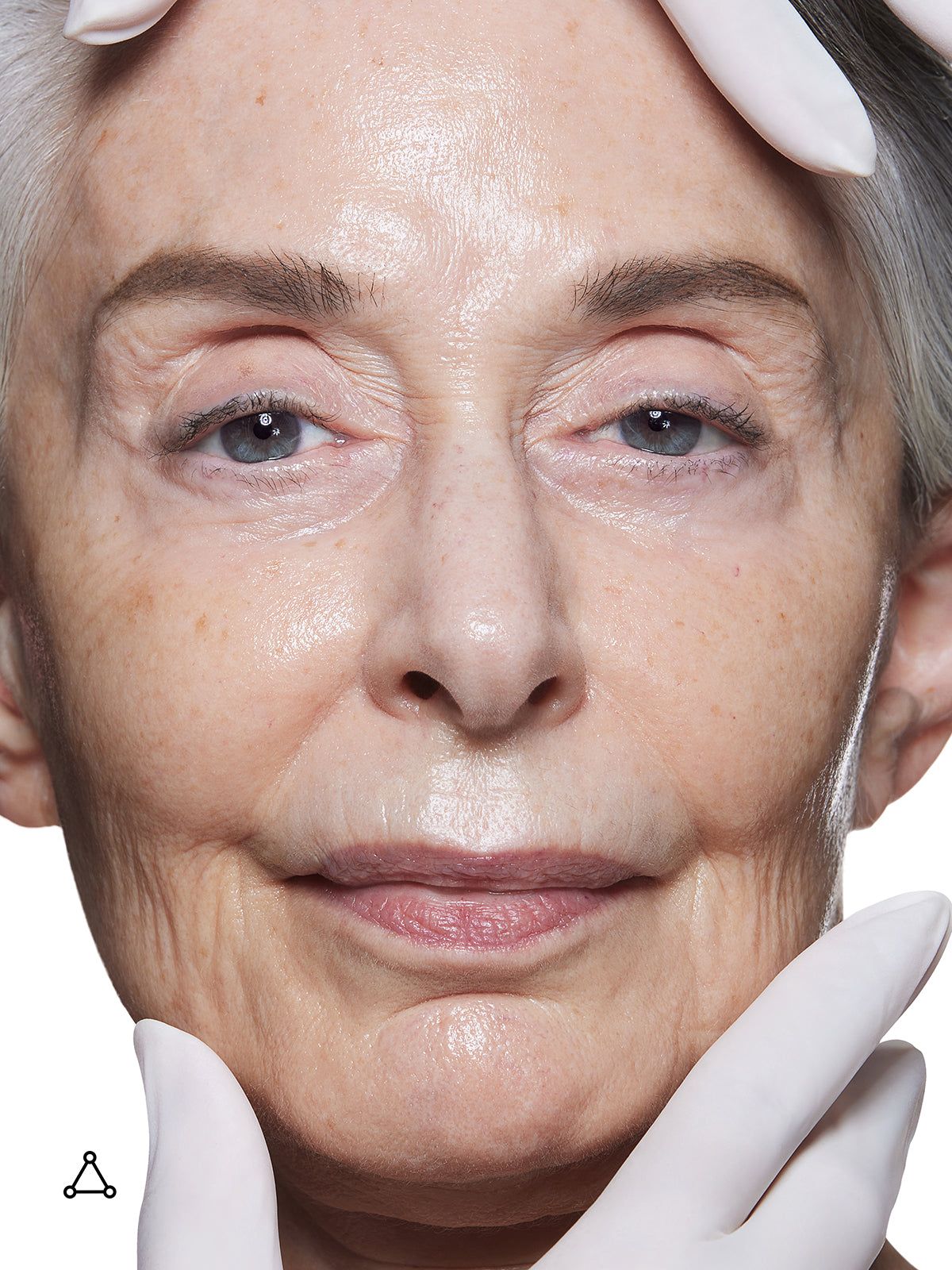 Viso di una donna anziana. Mani con guanti bianchi toccano il viso.