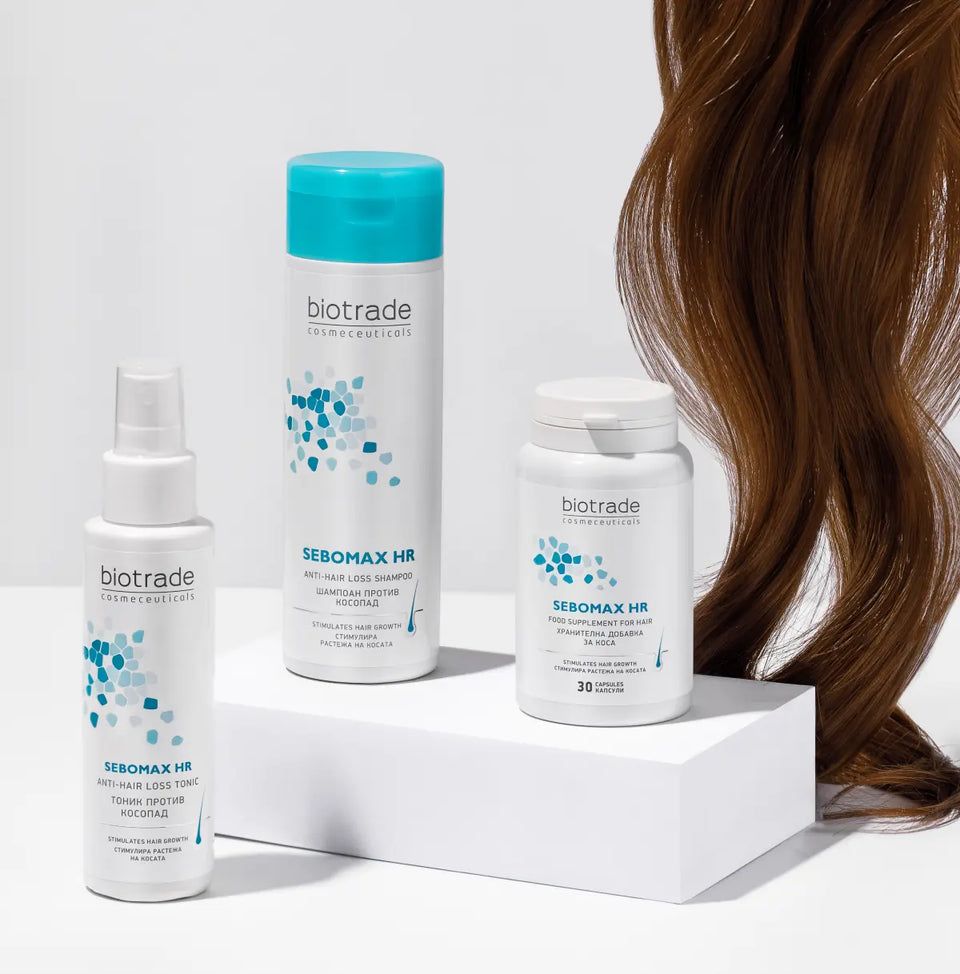 Tre prodotti Biotrade: shampoo, spray e compresse. Testo: Sebomax HR. Flaconi e scatola bianchi. Capelli castani sullo sfondo.
