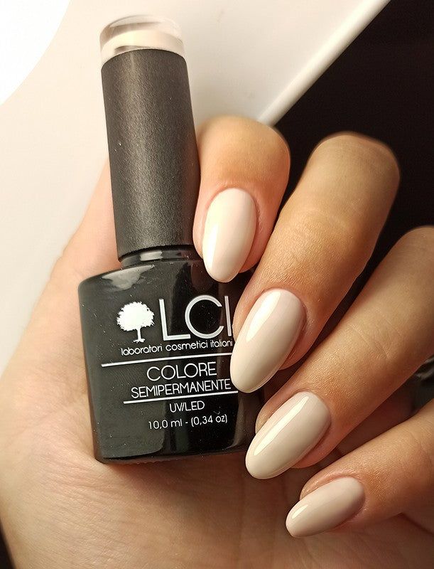 Flacone di smalto e unghie smaltate. Flacone nero. Unghie smaltate color nude.