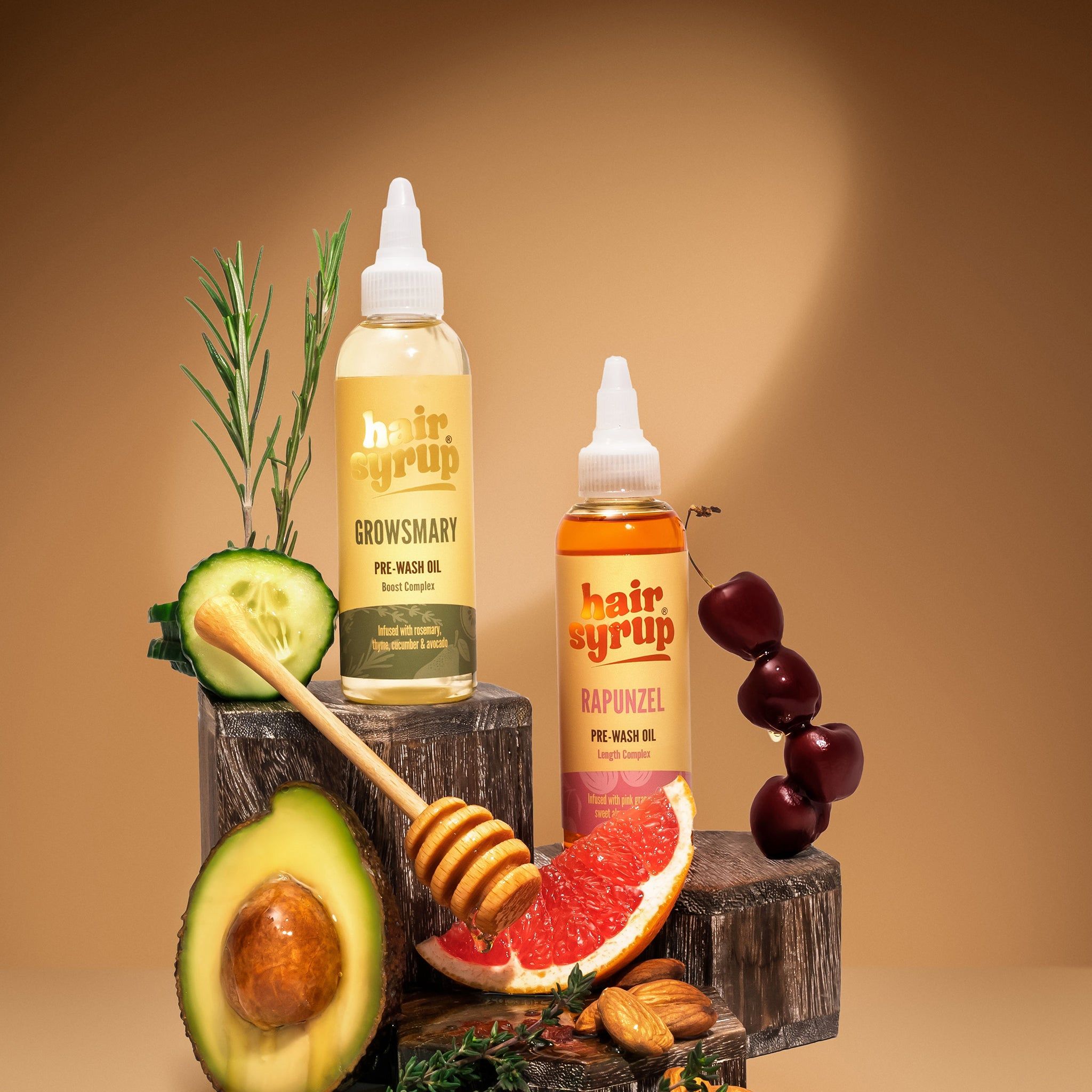 Due bottiglie Hair Syrup, una con 'Growsmary', l'altra 'Rapunzel'. Con avocado, miele e pompelmo.
