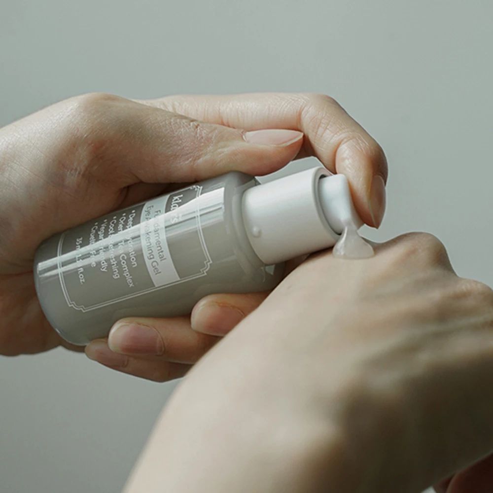 Mani che tengono flacone grigio Klairs. Il gel viene erogato dalla pompa.