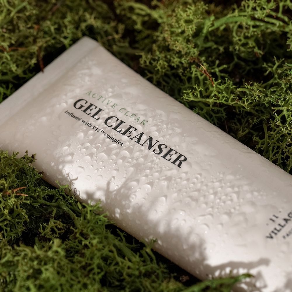 Tubo di gel detergente bianco con testo nero, su muschio verde. Gocce sul tubo.