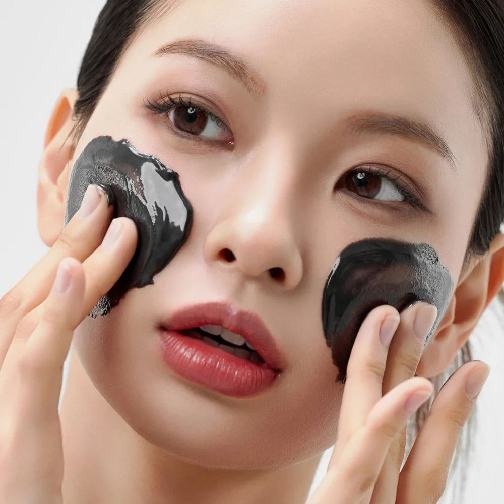 Persona con maschera nera sul viso. Mani che toccano la maschera. Sfondo bianco.