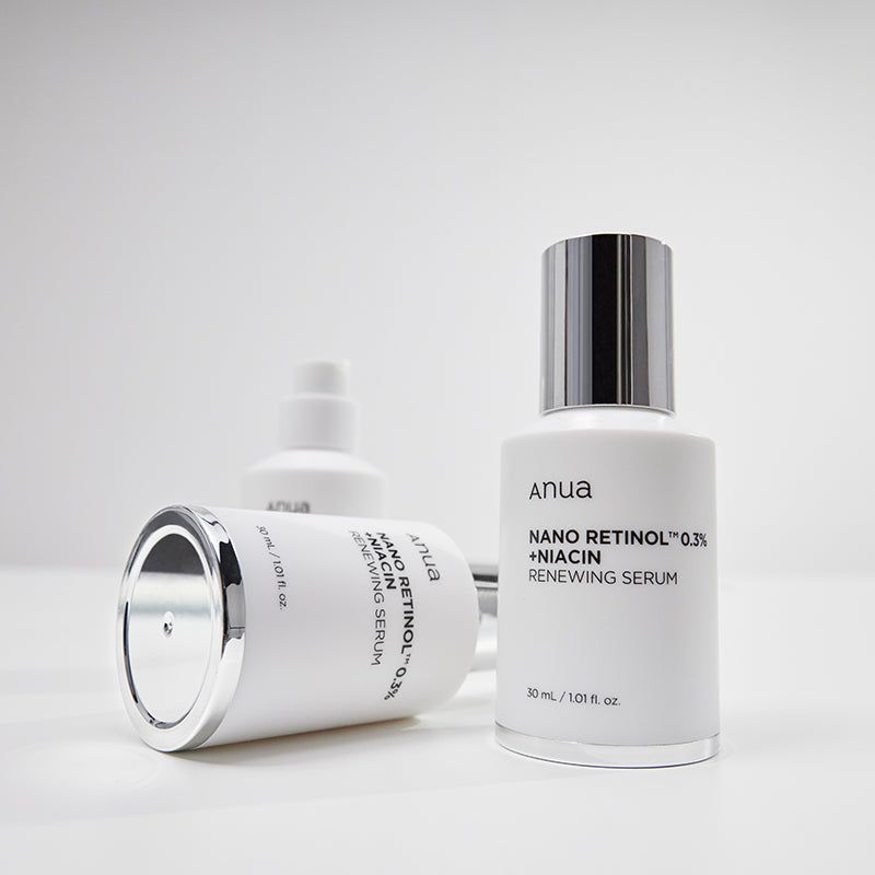 Tre flaconi bianchi con tappi argentati. Scritta: Anua, Nano Retinol 0.3% + Niacin Renewing Serum. Su sfondo bianco.