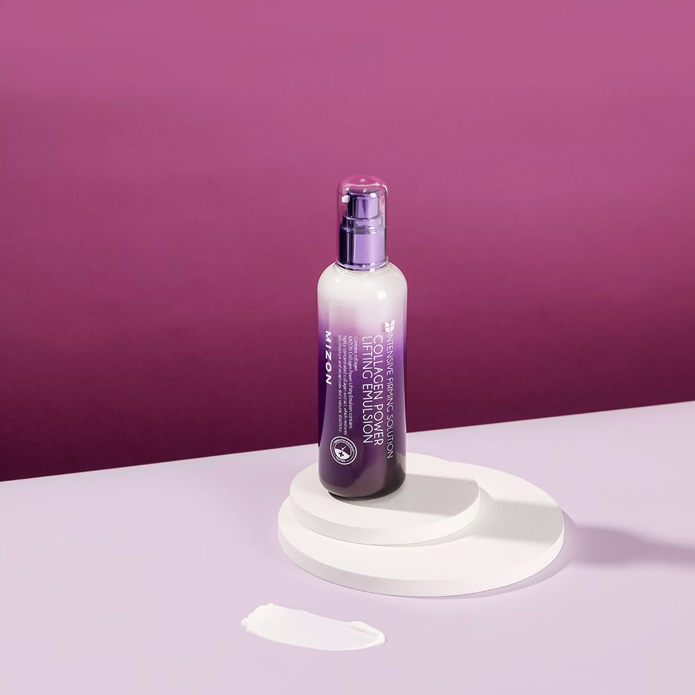 Flacone MIZON Collagen Power Lifting Emulsion su piedistallo. Macchia di crema. Testo: Collagen Power Lifting Emulsion.