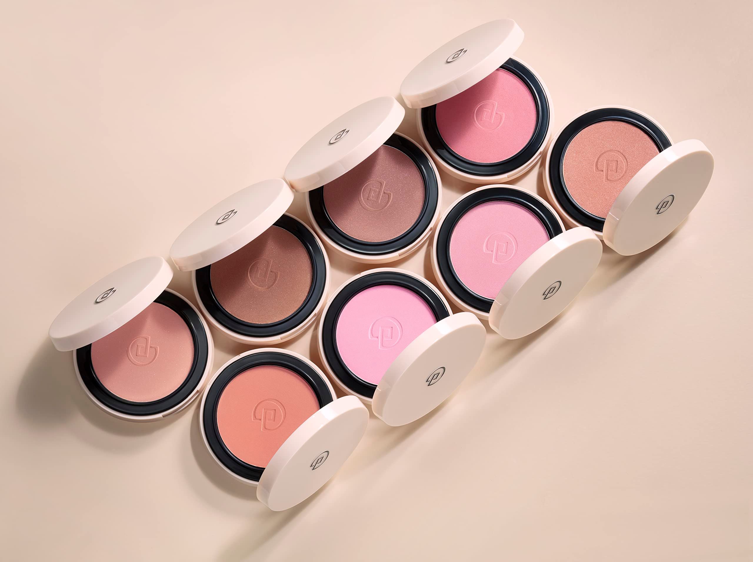 Diversi blush compatti con coperchi aperti. Diverse tonalità di rosa. Disposti su sfondo chiaro.