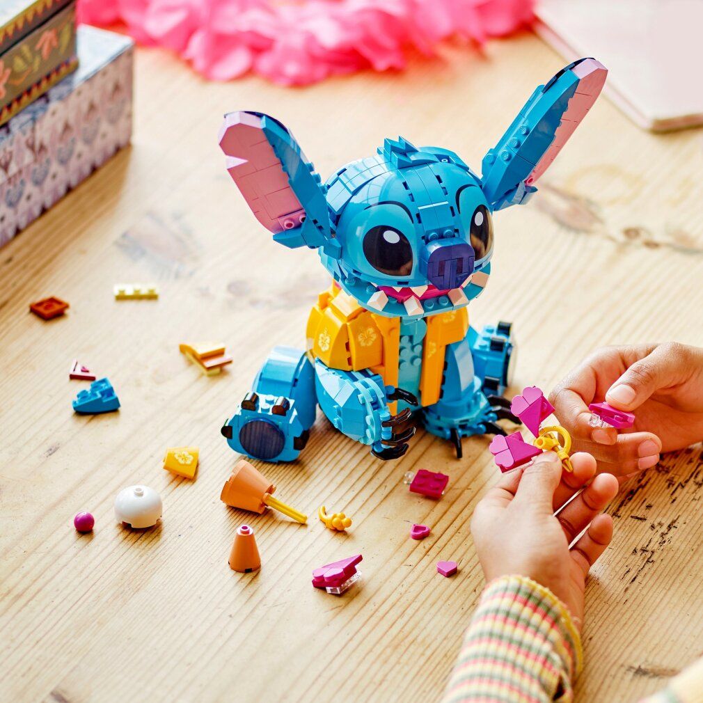 LEGO Stitch blu con orecchie rosa e fiore. Parti e mani durante la costruzione.