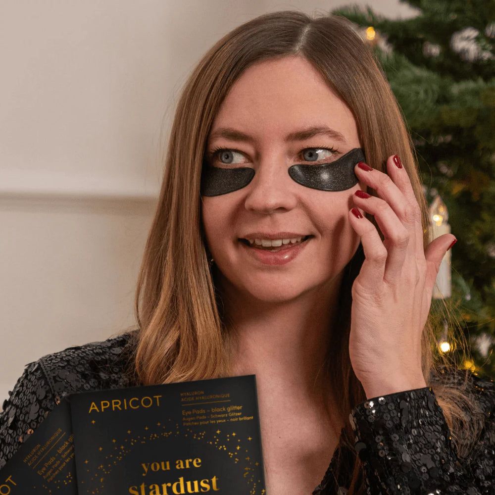 Donna con eye pads neri e confezione. Scritta: APRICOT, "you are stardust".