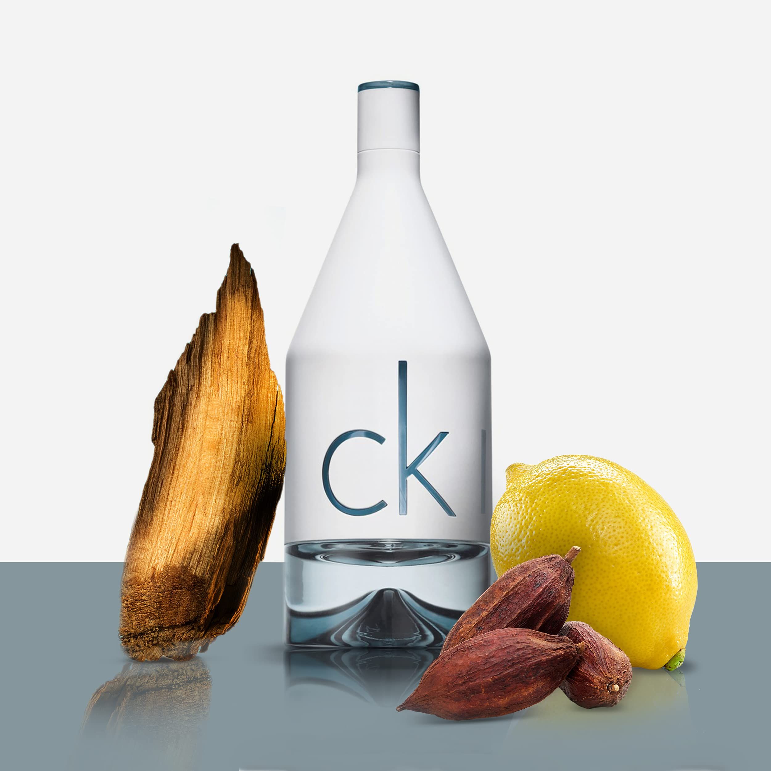 Flacone bianco con "ck" e ingredienti: legno, limone e fave di cacao.