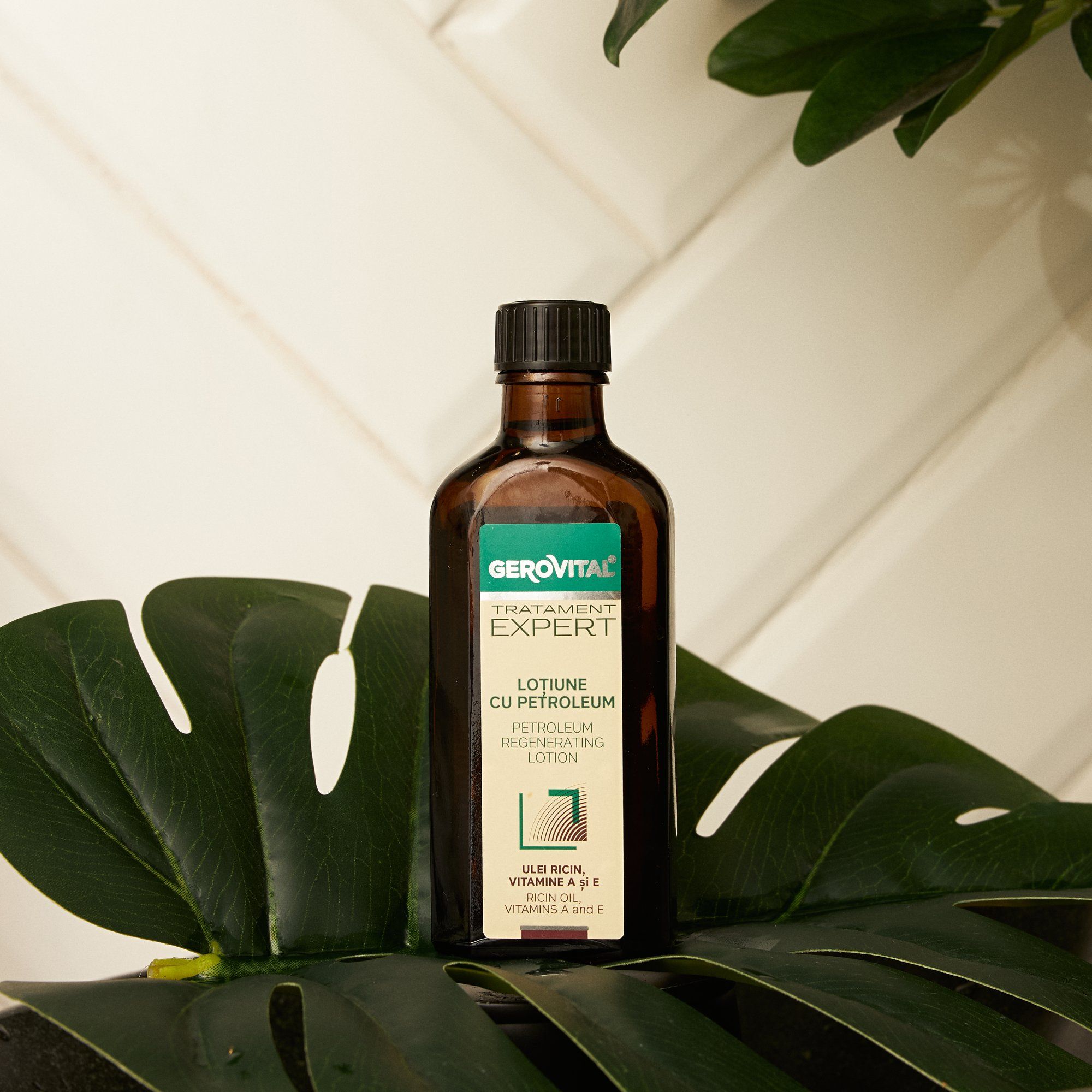 Bottiglia marrone con tappo nero su una foglia verde. Scritta: Gerovital, Tratament Expert, Lotiune cu Petroleum.