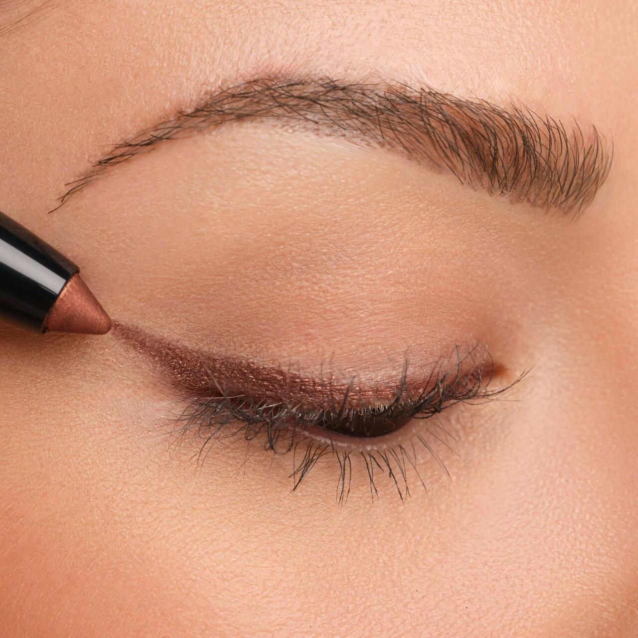 Occhio con Artdeco High Performance Eyeshadow Stylo applicato. Linea di ombretto marrone sulla linea delle ciglia superiori.