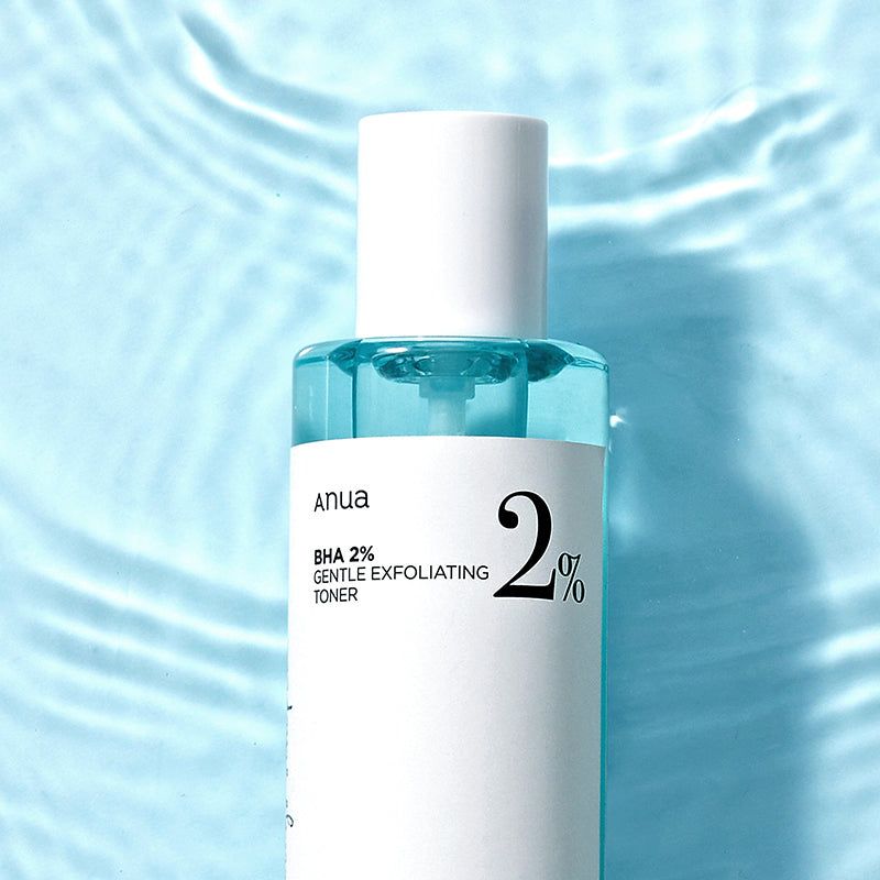 Primo piano del toner. Liquido blu in una bottiglia bianca. Scritta: Anua BHA 2% Gentle Exfoliating Toner.