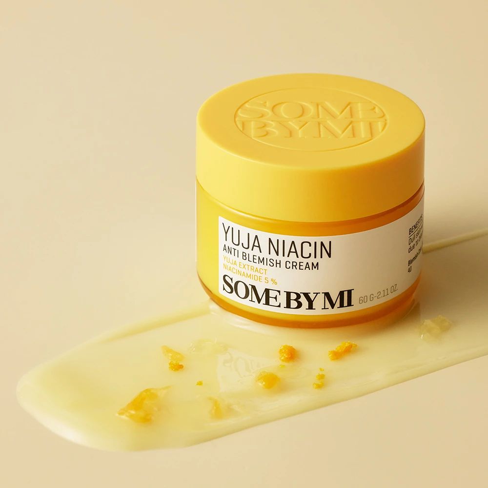 Vasetto giallo SOME BY MI Yuja Niacin Anti Blemish Cream. Crema e pezzi di frutta accanto. Testo visibile.