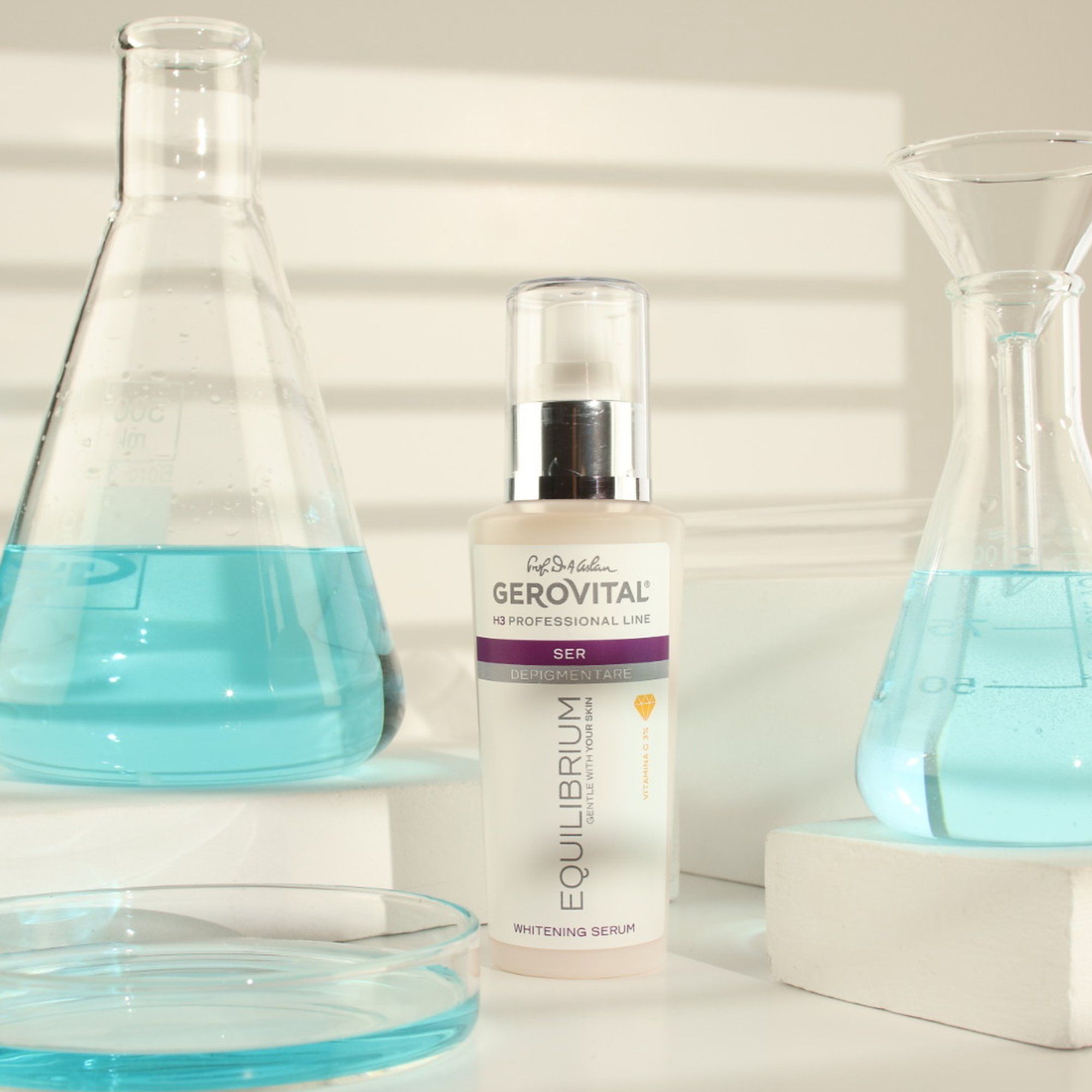 Flacone di siero con erogatore argento. Scritta: Gerovital, Equilibrium, Vitamina C. Circondato da vetreria da laboratorio con liquido blu.
