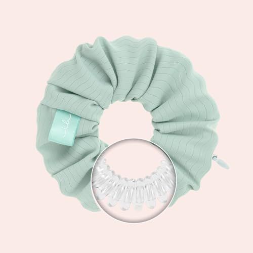 Elastico per capelli verde chiaro con superficie ondulata. Vista dettagliata dell'elemento a spirale interno. Su sfondo rosa.
