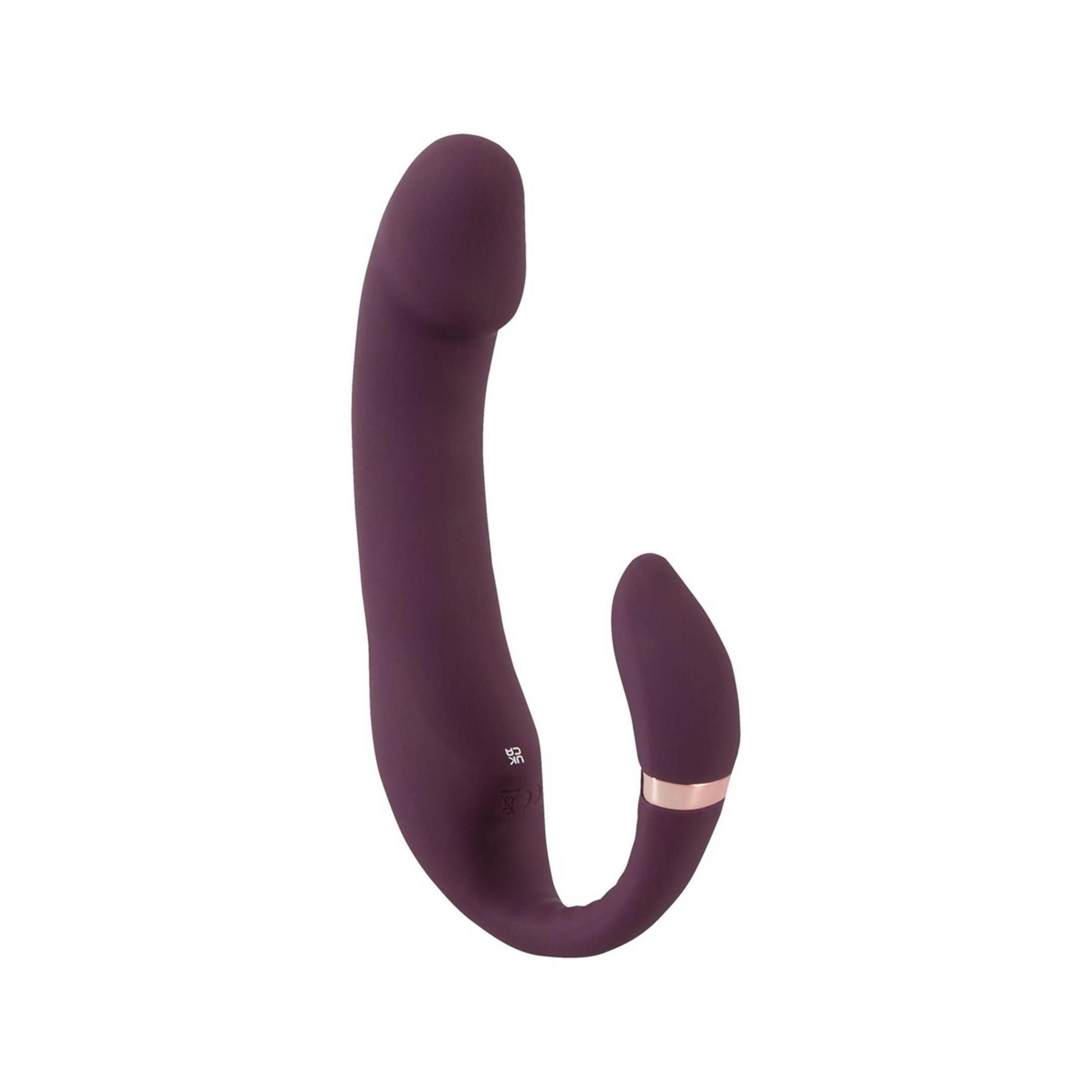 Vibratore viola a forma di U. Con un accessorio stimolatore e un anello dorato. Su sfondo bianco.