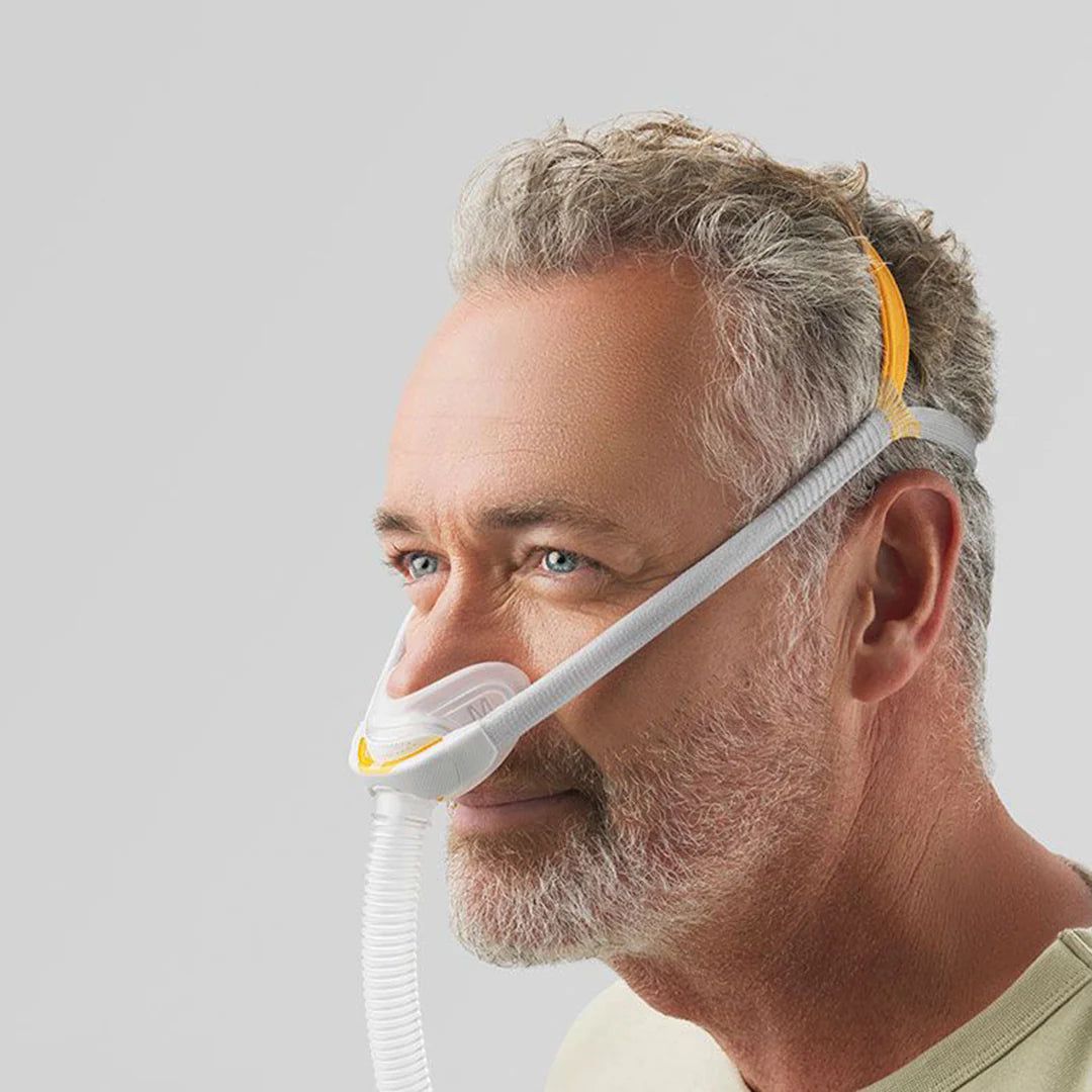 Uomo che indossa una maschera nasale grigia e gialla con tubo e fascia.