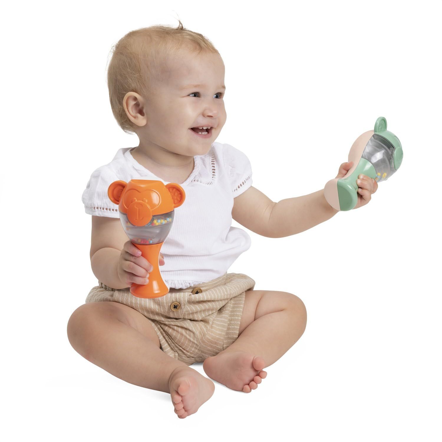 Un bambino tiene in mano due sonagli scimmia colorati, uno verde e uno arancione.