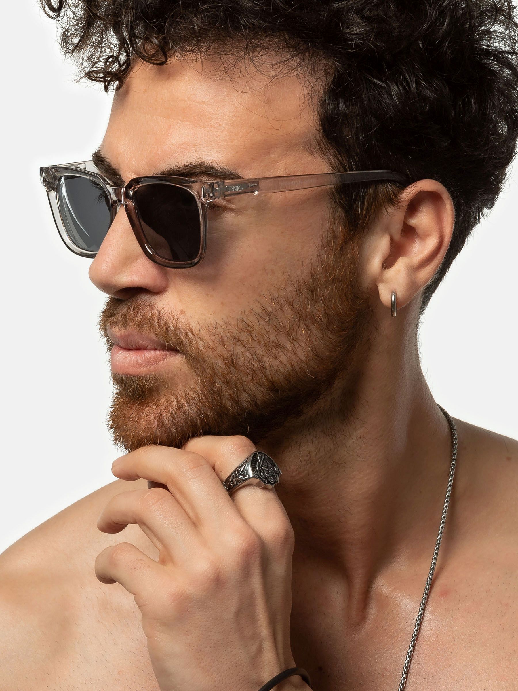 Uomo con occhiali da sole Twig. Montatura grigia, lenti rettangolari. Vista laterale.