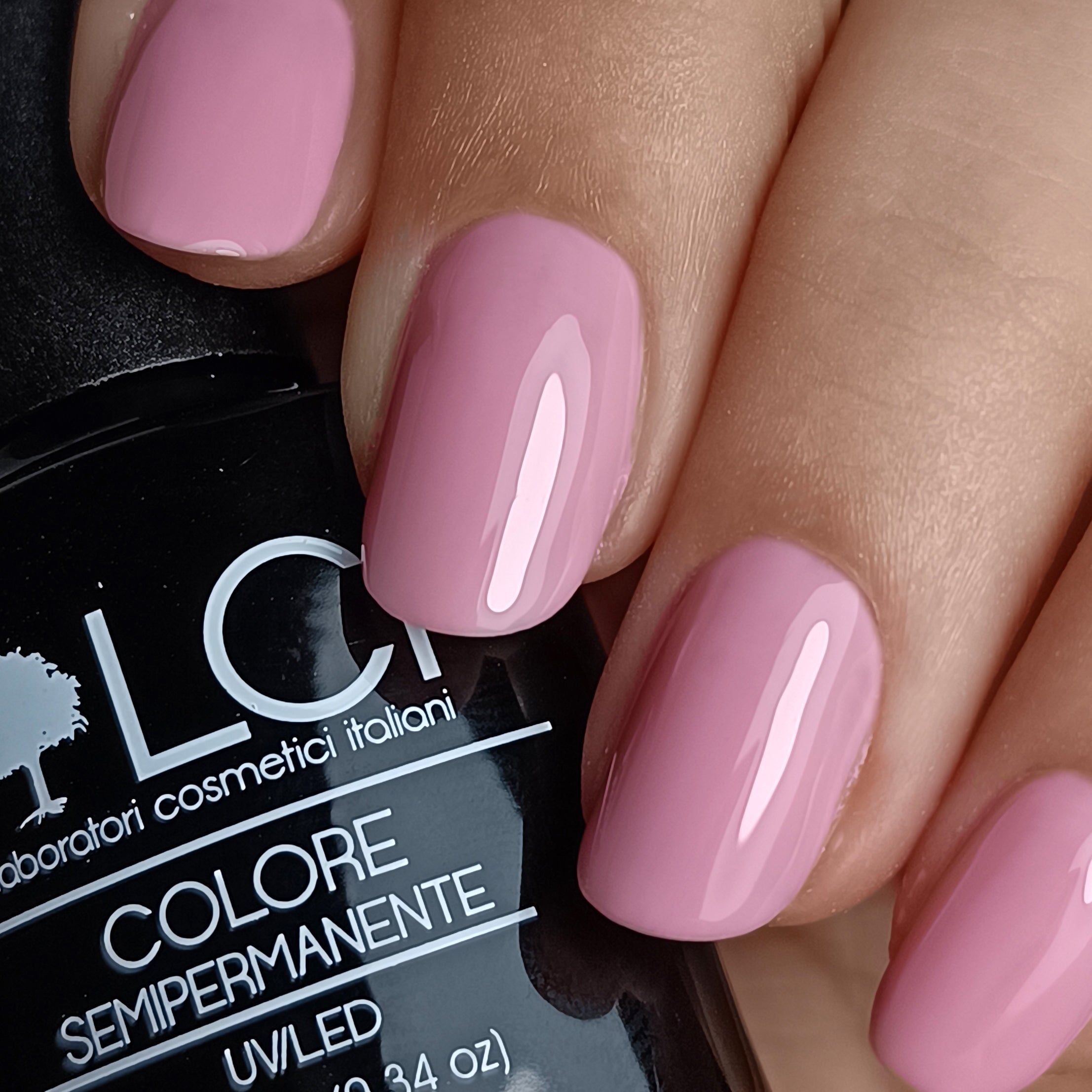 Mano con unghie rosa smaltate. Flacone con scritta: LCI, Colore Semipermanente, UV/LED.