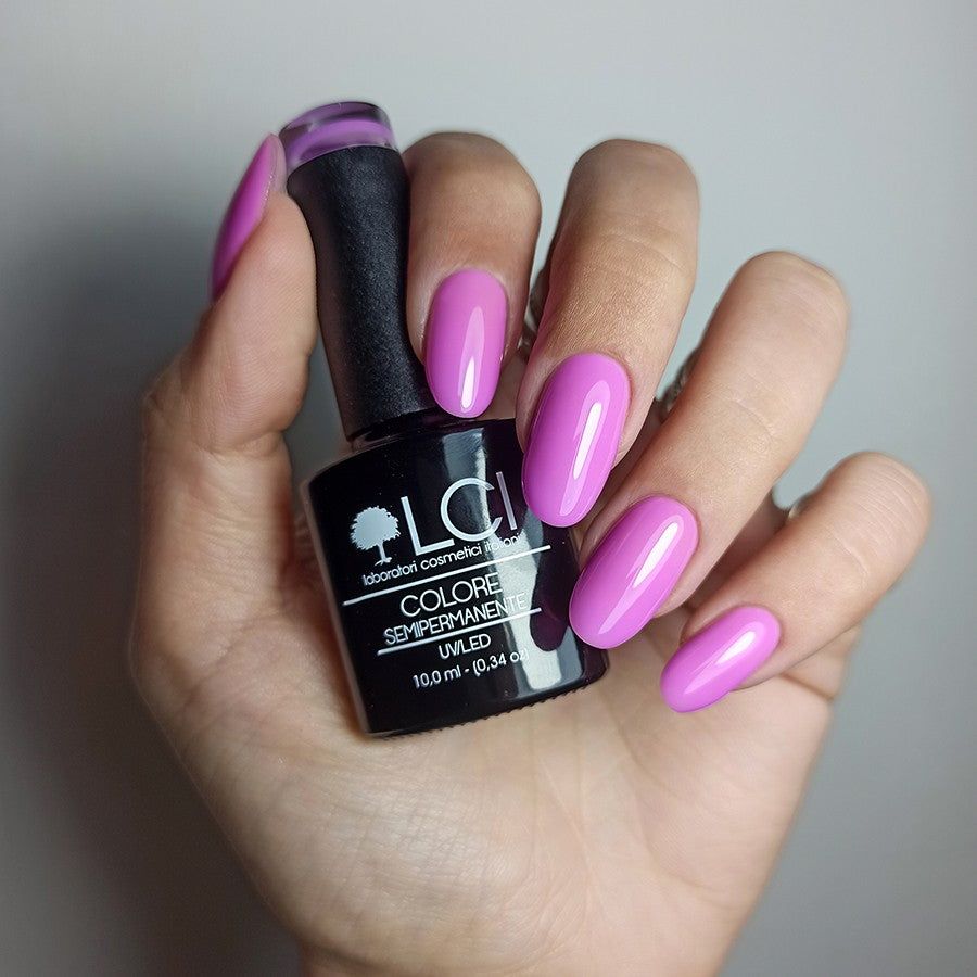 Mano con flacone smalto e unghie viola. Scritta: LCI, Colore Semipermanente, UVLED 10,0 ml.