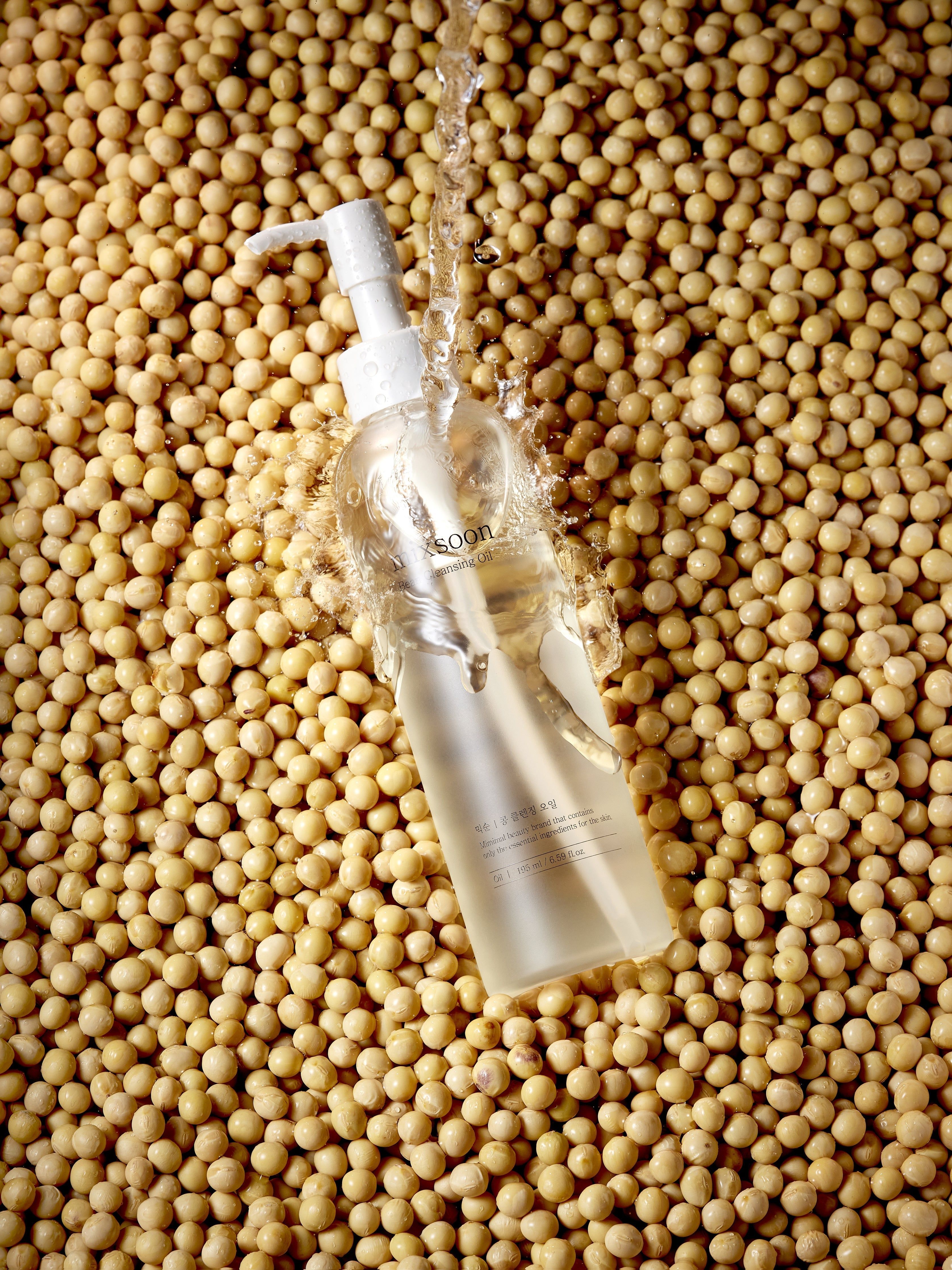 Flacone di olio detergente mixsoon Bean in mezzo a semi di soia, irrorato d'acqua.