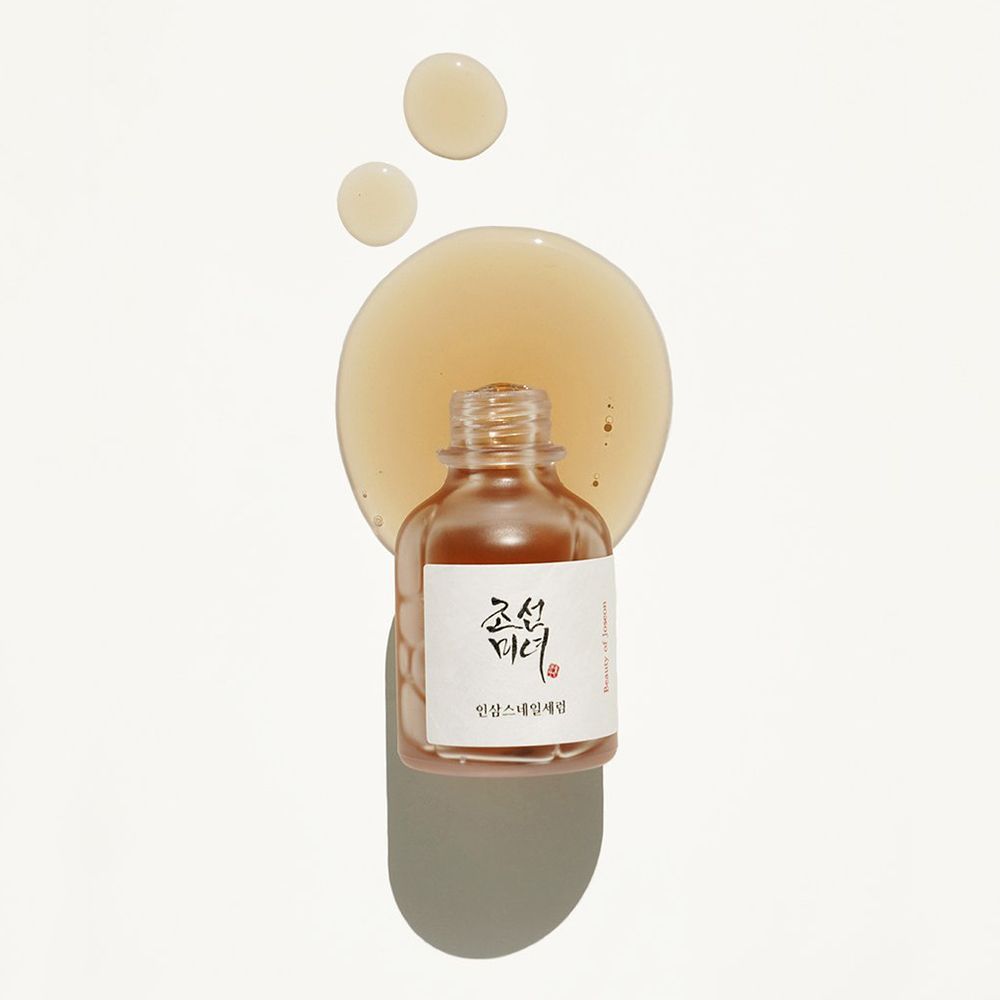 Flacone trasparente con siero e gocce. Etichetta con scritta coreana. Su sfondo chiaro.